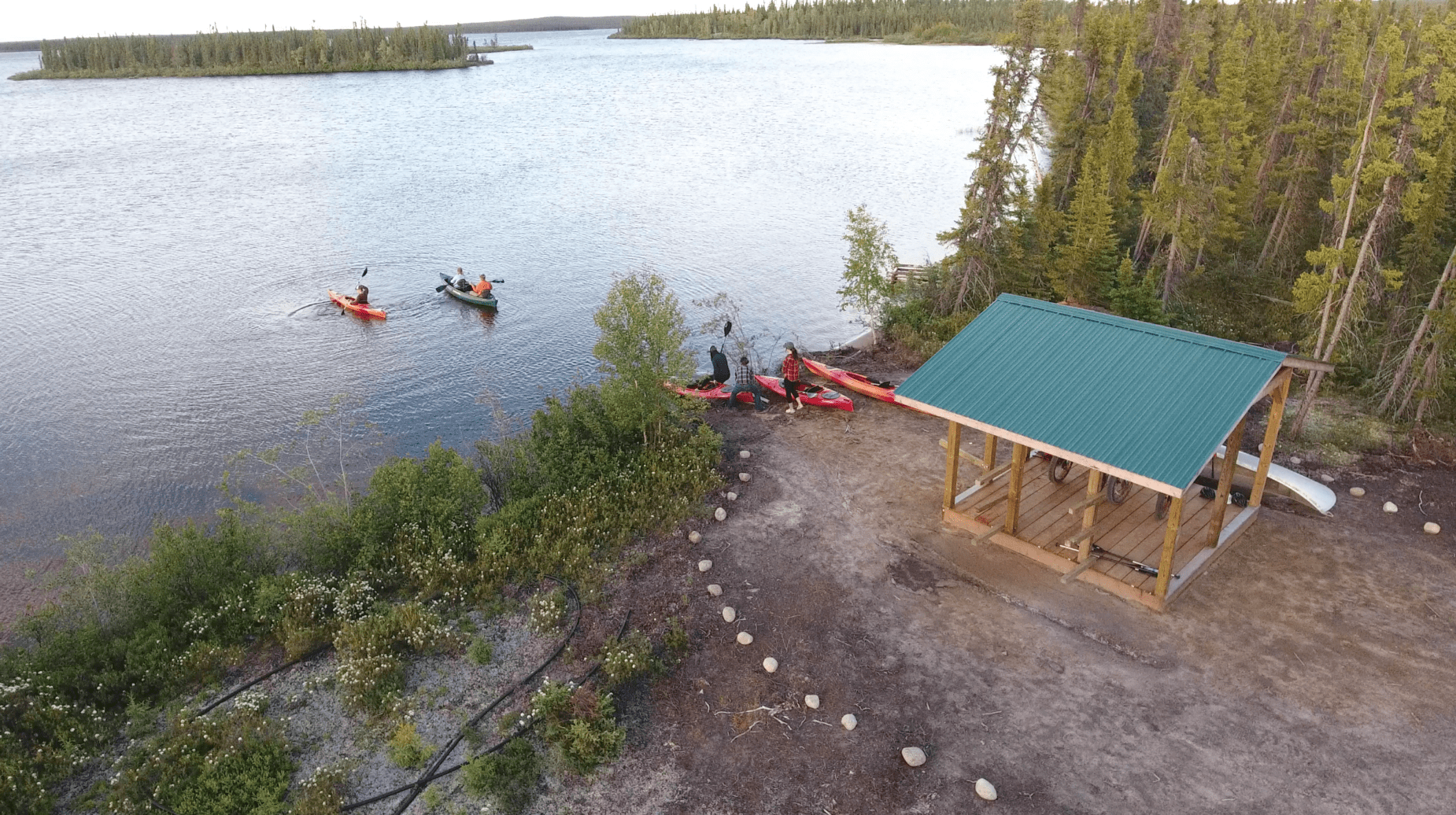 Birds eye view of a group of people launching 3 kayaks and 1 canoe