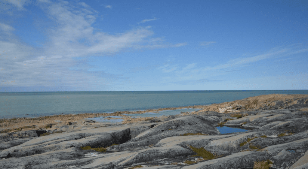 landscape image over the rocks looking over the small beach and surrounding water